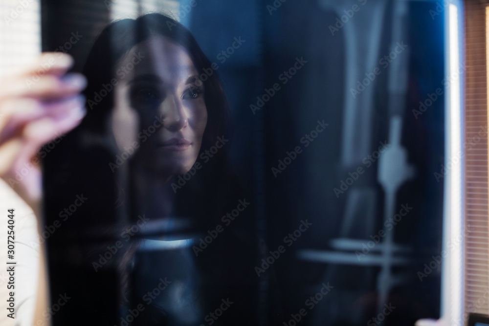 A picture of a beautiful young woman doctor. The doctor is standing in the tomography room and studying the x-ray picture. Professional people at work. A picture of a beautiful young woman doctor. The doctor is standing in the tomography room and studying the x-ray picture. Professional people at work.
