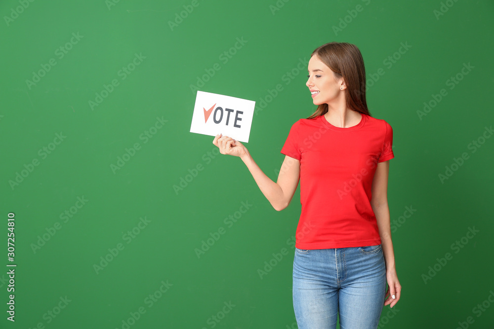 Young woman holding paper with text VOTE on color background Young woman holding paper with text VOTE on color background