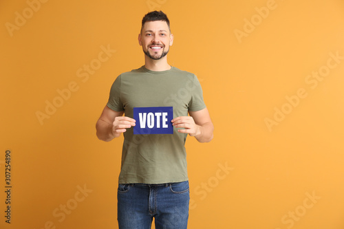 Man holding paper with text VOTE on color background © Pixel-Shot