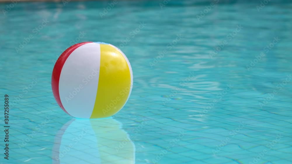 Colorful inflatable beach ball floating in swimming pool. Summer ...