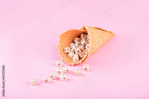 Waffle cone with alphabet inside over pink background