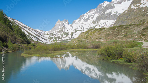 Mountains peaks mirroring in the lake showing symmetry. Mountains are full of snow and the water is calm. Val Veny, Italy