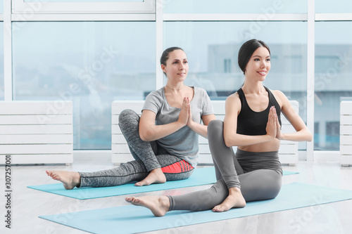 Sporty young women practicing yoga in gym