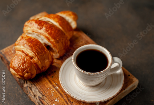 coffee and a large sliced ​​croissant on a stone table, close-up, early breakfast concept