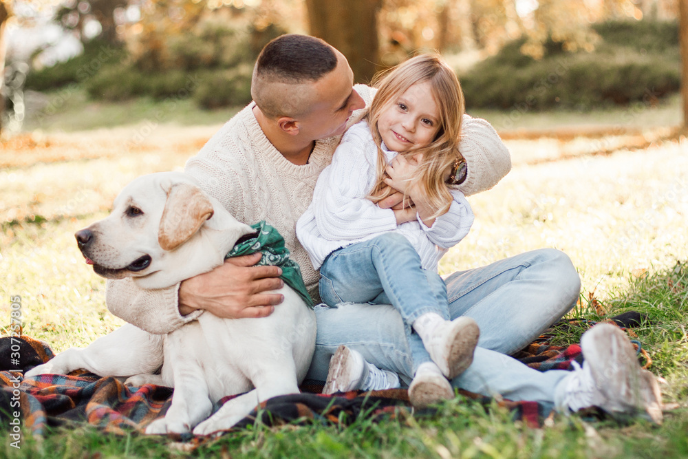 Happy beautiful family with dog labrador is having fun are sitting on green grass in park. Happy beautiful family with dog labrador is having fun are sitting on green grass in park.