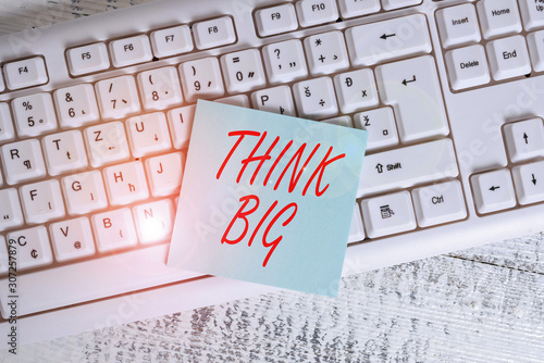 Conceptual hand writing showing Think Big. Concept meaning To plan for something high value for ones self or for preparation Keyboard office supplies rectangle shape paper reminder wood photo