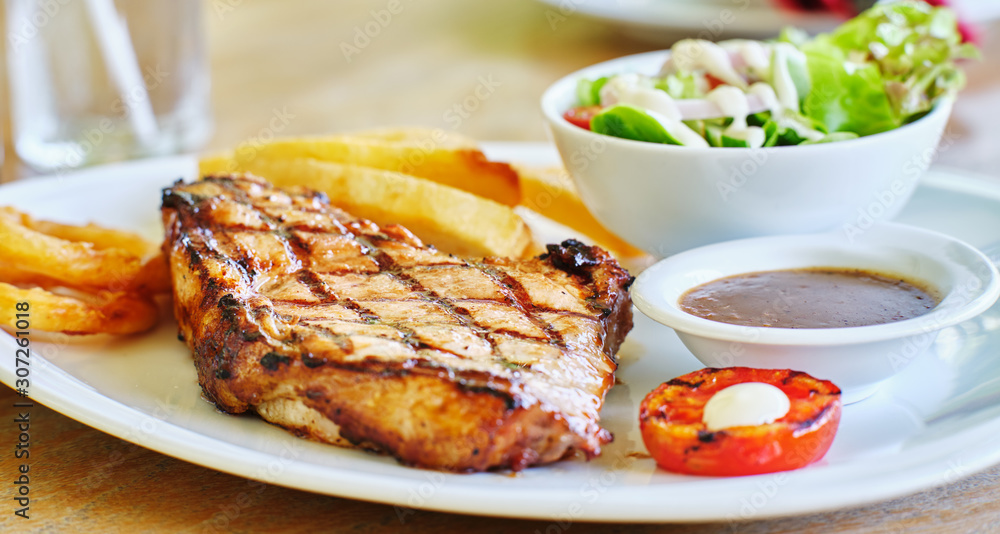 thick pork steak with gravy, salad and hand cut fries thick pork steak with gravy, salad and hand cut fries