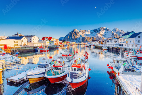 Fototapeta Naklejka Na Ścianę i Meble -  Beautiful Winter nature scene of fishing town on Lofoten Islands in Norway. Amazing sunny landscape of traditional houses rorbu and fishing boats in harbor.