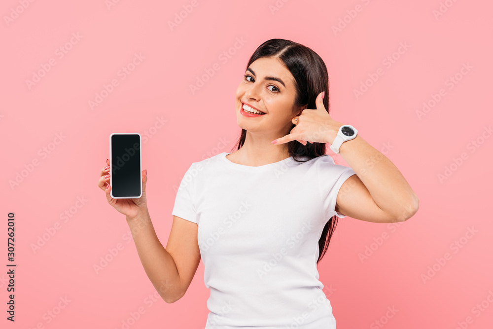 smiling pretty brunette girl holding smartphone with blank screen and showing call gesture isolated on pink smiling pretty brunette girl holding smartphone with blank screen and showing call gesture isolated on pink
