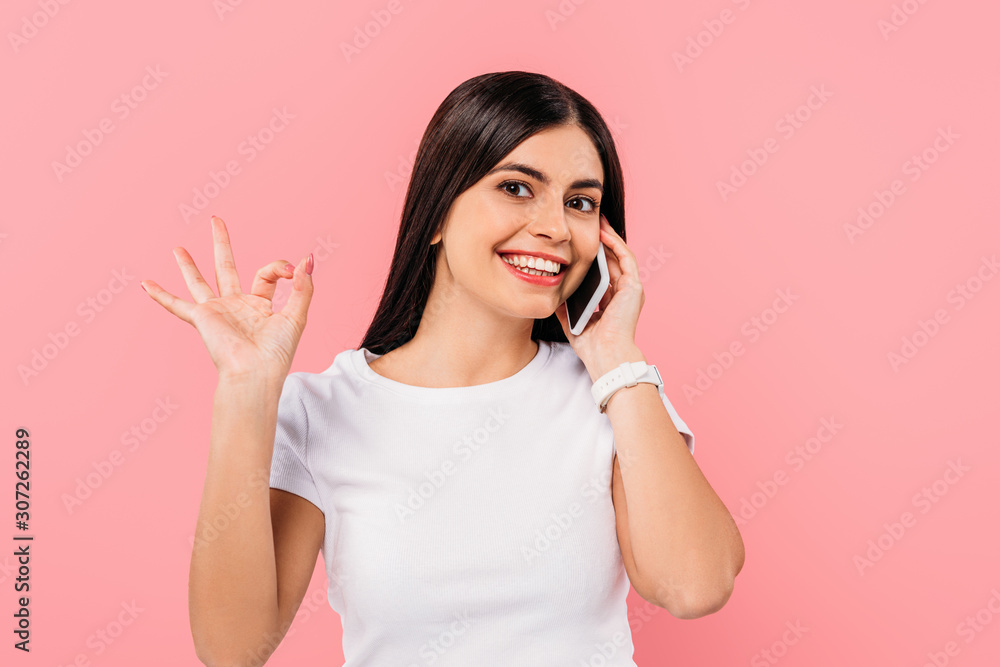 smiling pretty brunette girl talking on smartphone and showing ok isolated on pink smiling pretty brunette girl talking on smartphone and showing ok isolated on pink