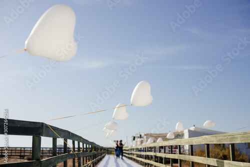 White Air Balloons heart shaped flying in blue sky. Love concept. Holiday celebration.