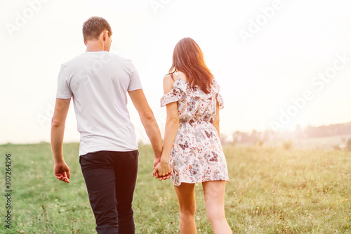 Young couple in love walking on through grass field. Walking along grass field. © zadorozhna