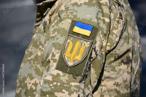 Ukrainian soldier wearing military uniform with flag and chevron depicting trident - Ukrainian emblem and national symbol