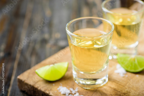 Tequila in a shot glass on a brown wooden background prepared for a party