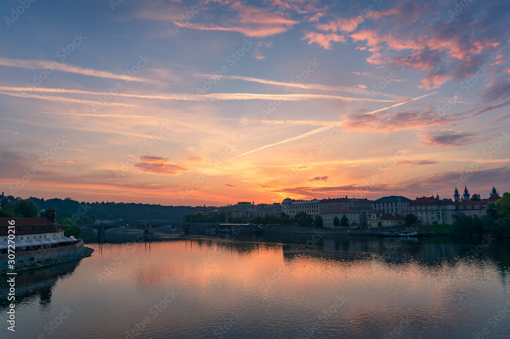 Sunrise in Prague with Vltava river and historic waterfront buildings