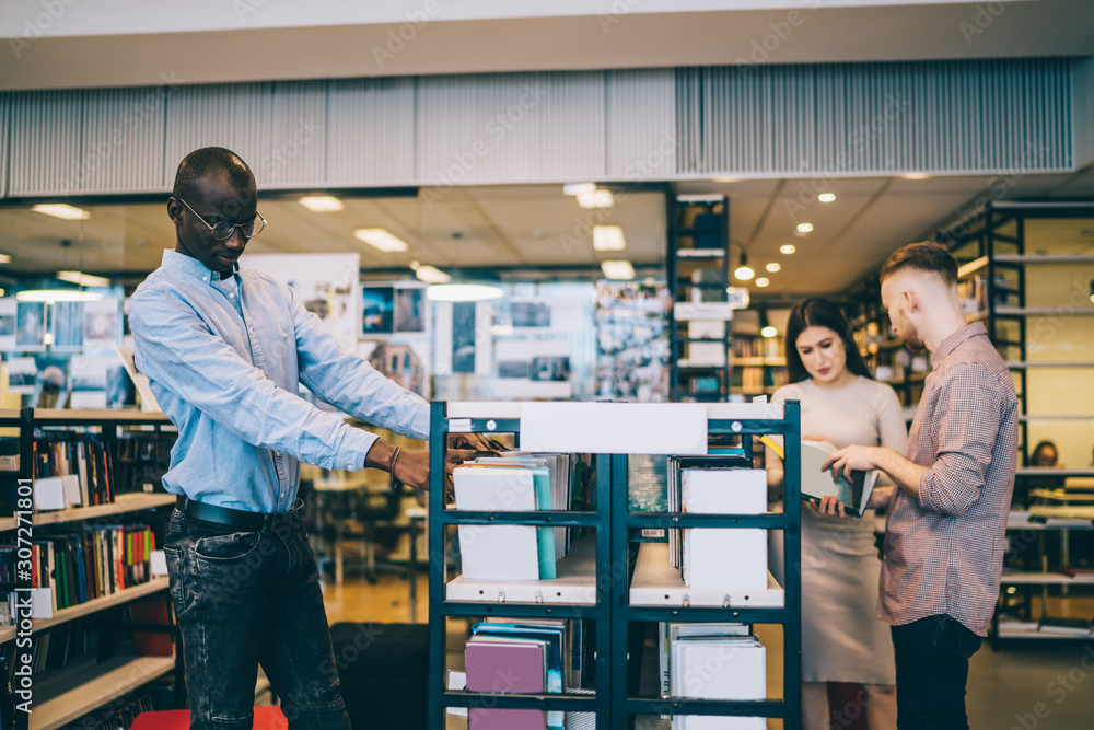 Black student choosing books near classmates Black student choosing books near classmates