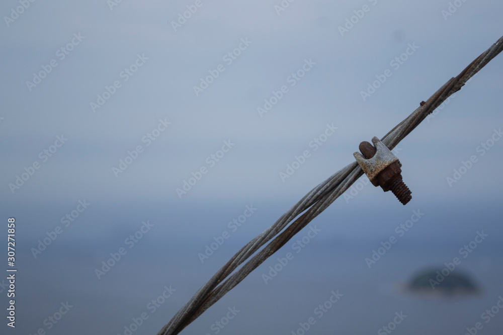 Metal cable with rusty screw on a gray sky Metal cable with rusty screw on a gray sky