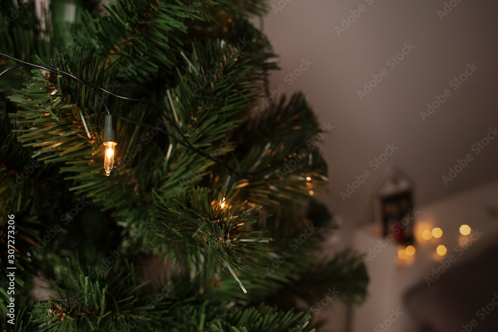 Beautiful Christmas tree near the bedroom. Christmas tree with light decorations . Preparation for Christmas and New Year. Lifestyle. image. Christmas background.Winer holiday. Close up. Detail. Beautiful Christmas tree near the bedroom. Christmas tree with light decorations . Preparation for Christmas and New Year. Lifestyle. image. Christmas background.Winer holiday. Close up. Detail.