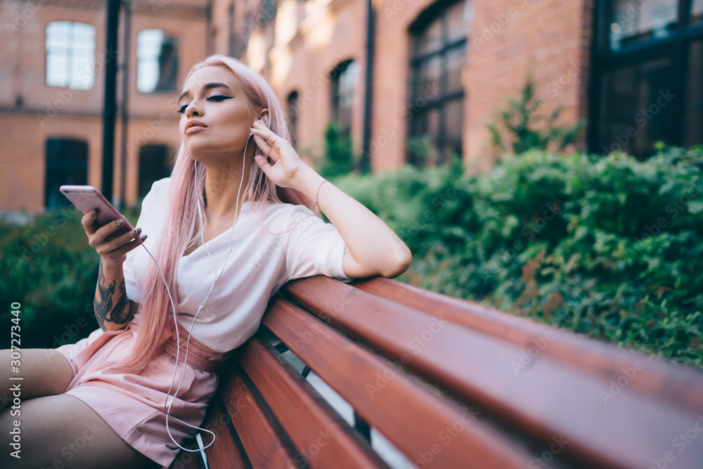 Fototapeta premium Alluring skinny woman enjoying music in street