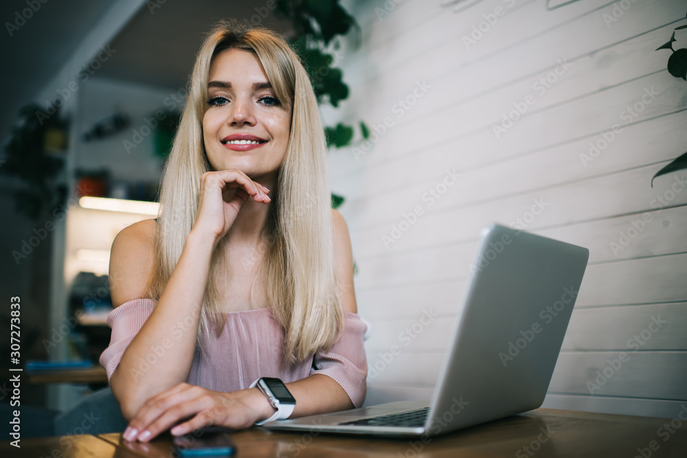 Smiling woman sitting at table with gadgets Smiling woman sitting at table with gadgets