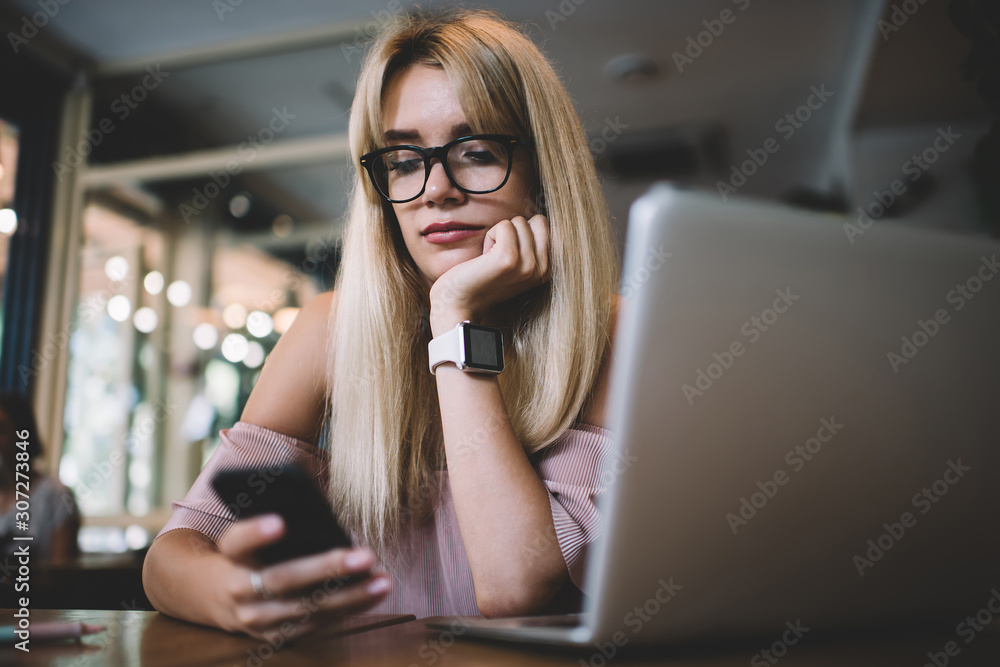 Pensive woman in eyeglasses reading message on mobile phone Pensive woman in eyeglasses reading message on mobile phone