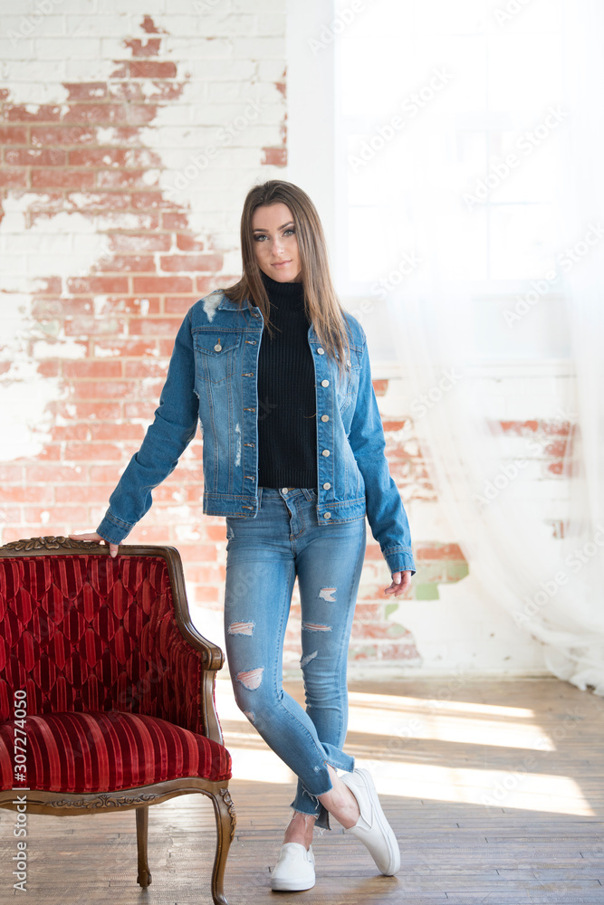 Stunning young brunette woman wearing denim jacket, black turtleneck and  blue jeans poses in studio Stock Photo | Adobe Stock