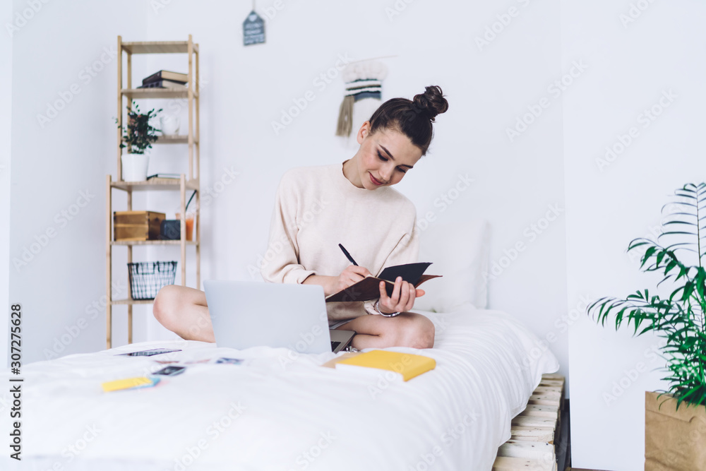 Joyful young woman learning on bed and smiling Joyful young woman learning on bed and smiling