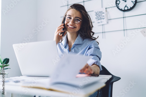 Young woman laughing while talking on cellphone in office photo
