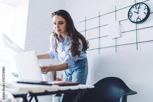 Young worker with paper drat looking at laptop photo