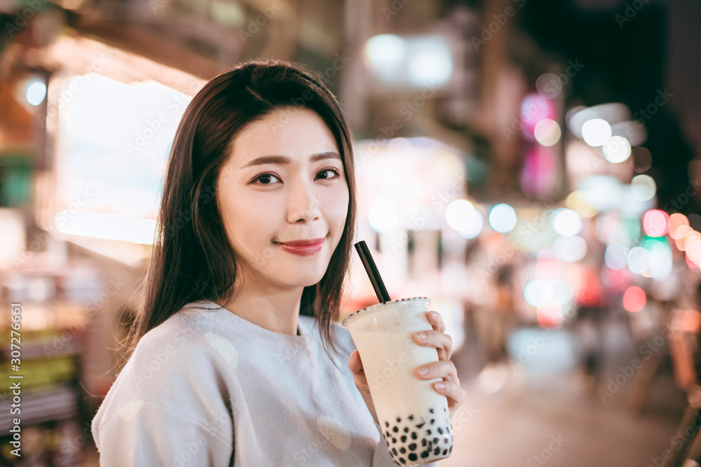 Asian woman enjoy bubble milk tea with street food in Night Market