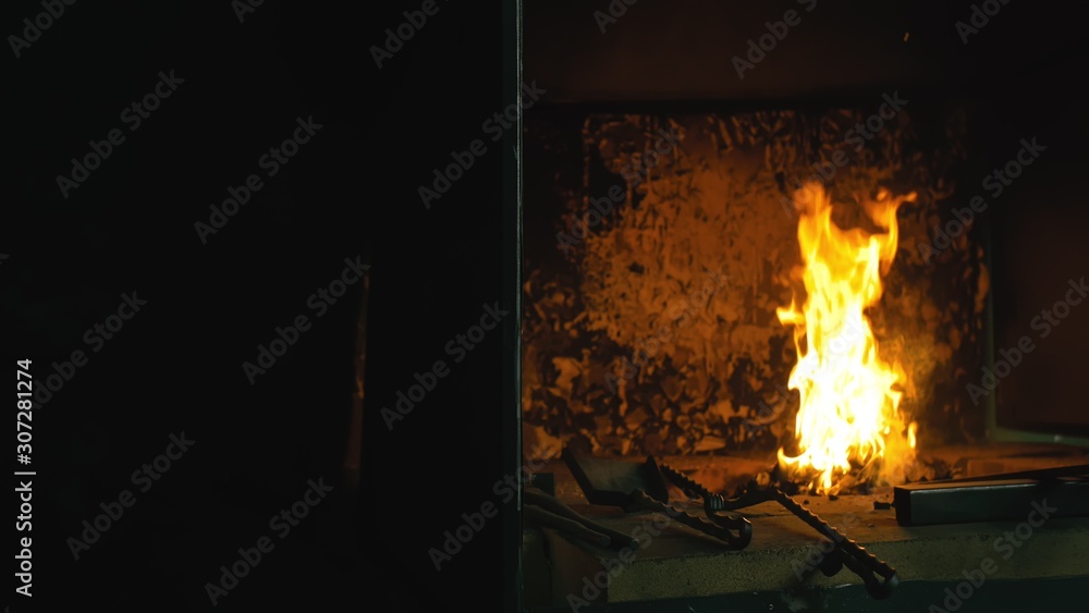 Forge fire in furnace. Blacksmith tempers a steel product in a stove. Smithy forging for hardening and heating iron. Blacksmith makes iron for manufacture of fireplace, stove. Burner Slow Motion.