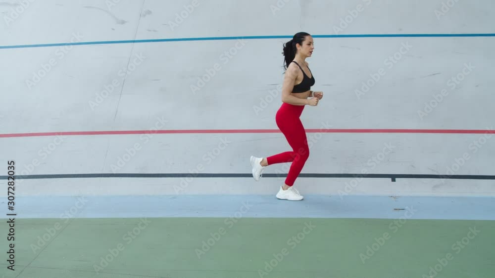 Fit girl running at cardio workout outdoor. Woman runner training on stadium Fit girl running at cardio workout outdoor. Woman runner training on stadium