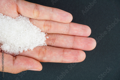 Top view of sugar on hand over black background. Health and care concept