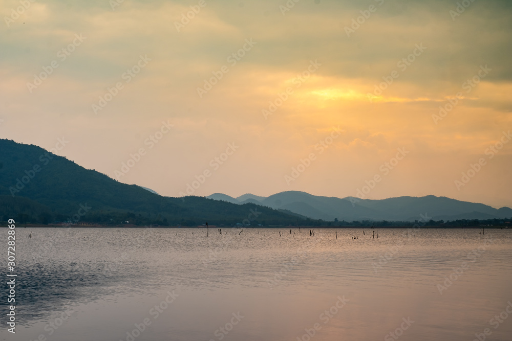 Landscape view of nature water river lake with mountain range and beautiful sunset sky background in Thailand.