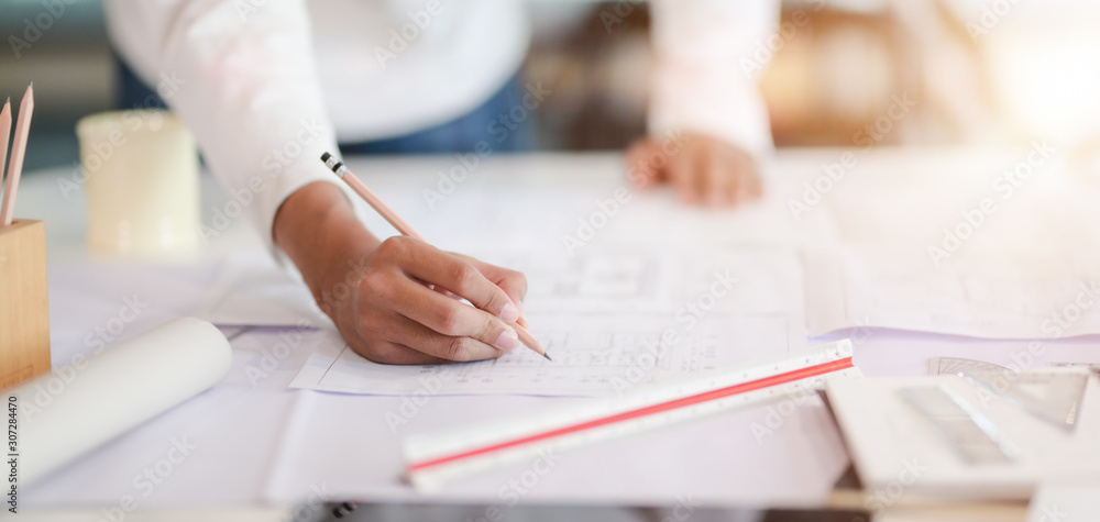 Cropped shot of professional architect working on the construction plan in modern office Cropped shot of professional architect working on the construction plan in modern office