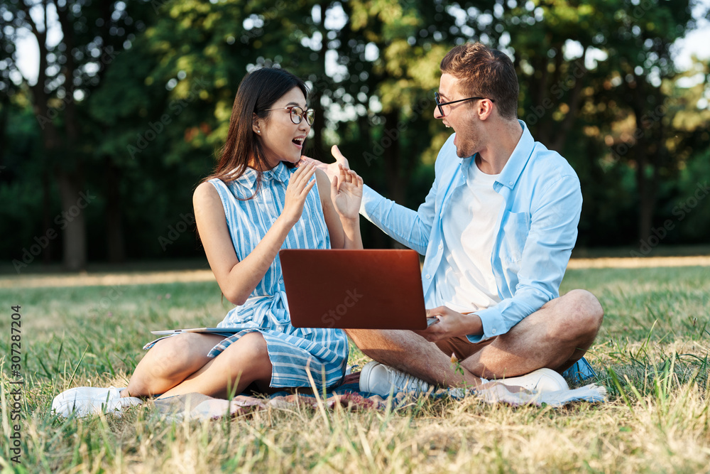 young couple with laptop in the park young couple with laptop in the park