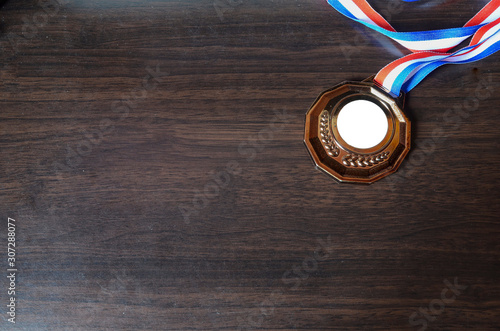 Bronze medal on wooden desk background. Selective focus.
