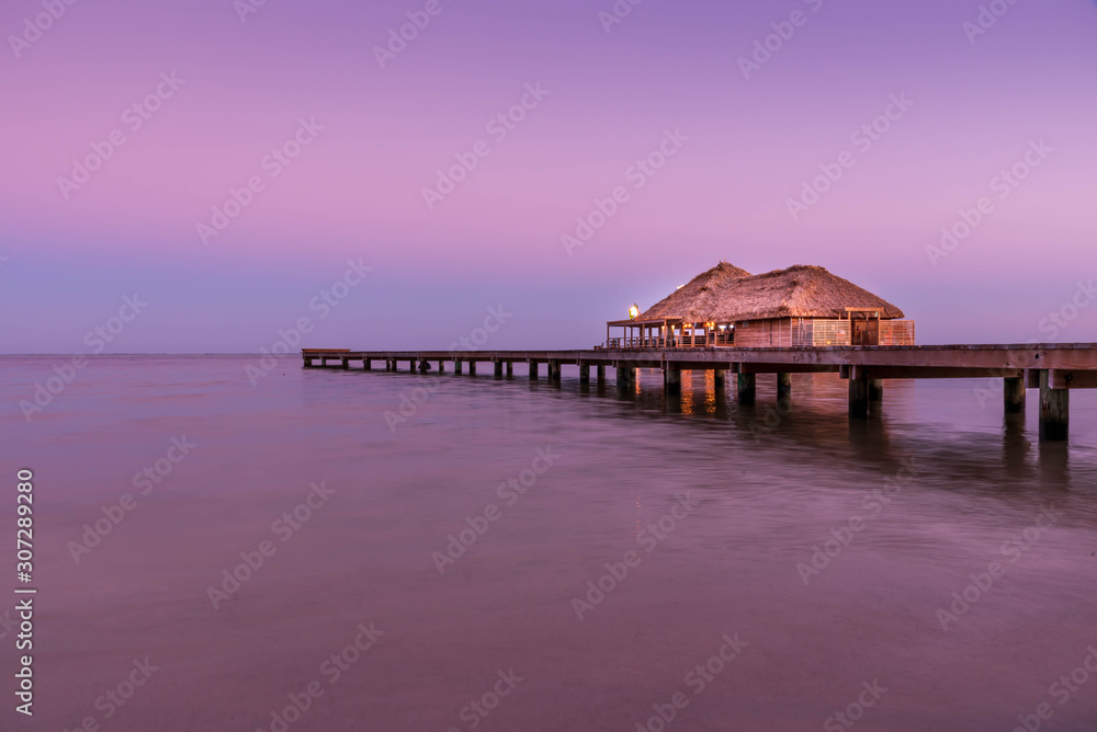 A view of the bungalow overwater beautifully lit up at dusk in Belize.