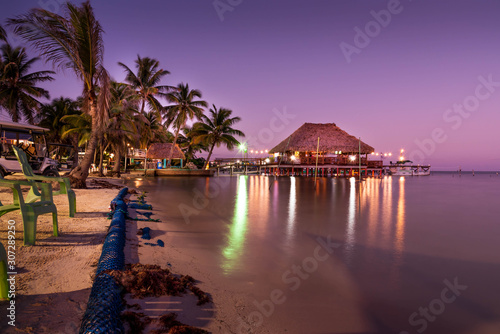 Slika na platnu A view of the bungalow overwater beautifully lit up at dusk in Belize