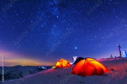 Great bright campsite with colorful tourist tents, on top in the Ukrainian Carpathian Mountains, at night with views of the stars and the Milky Way 