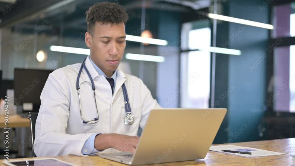 Focused Young Doctor Working on Laptop in Modern Office Focused Young Doctor Working on Laptop in Modern Office