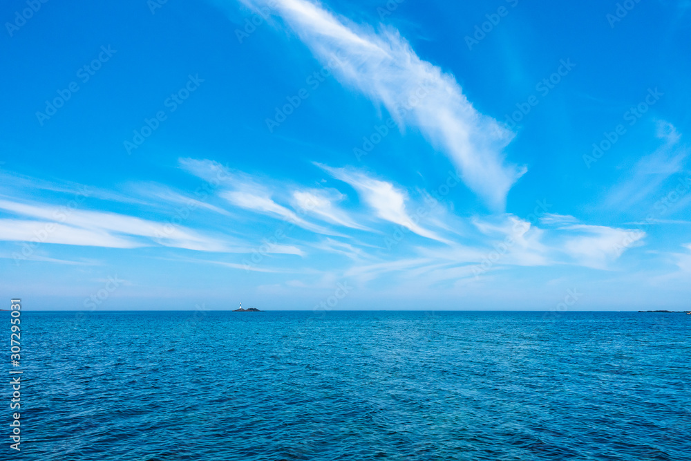 夏の青い海と青い空の間の離れ小島と灯台