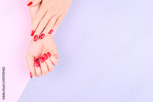 Woman hands with stylish red manicure on pastel lilac and pink background. Holiday, party and beauty concept. Horizontal © Ekaterina_Molchanova