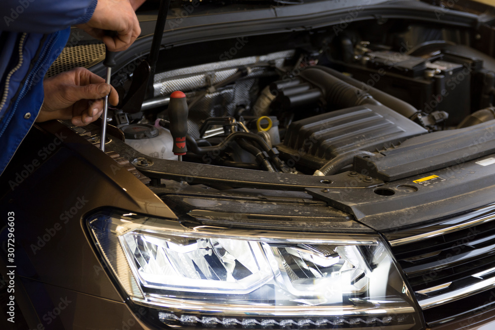A mechanic adjusts the headlights on a car. Diode headlight of a modern