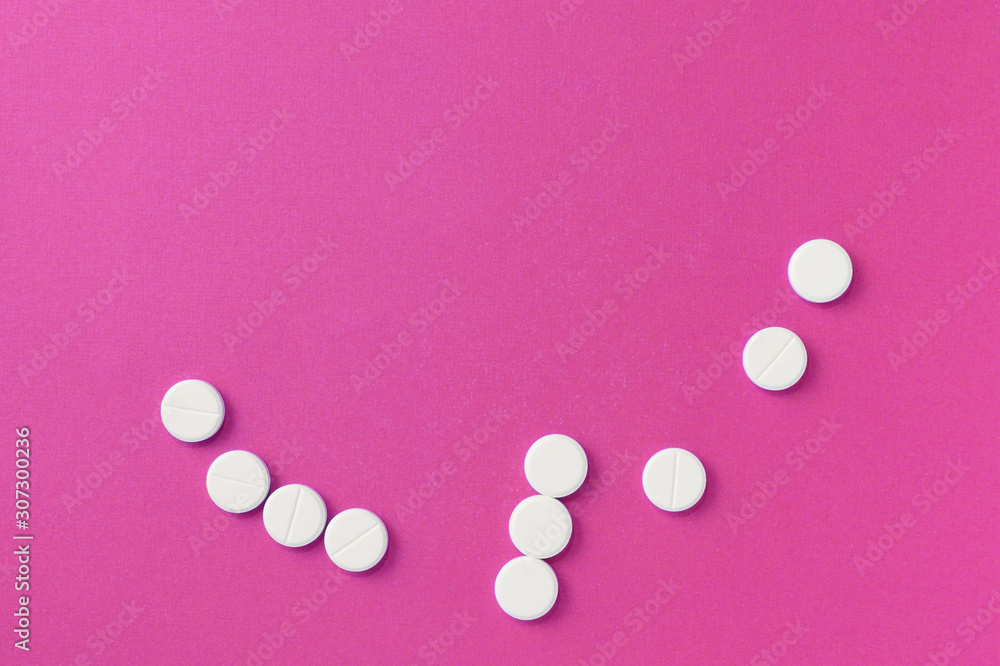 White round pills tablets on a bright pink background close up. Top view, copy space. Medical concept White round pills tablets on a bright pink background close up. Top view, copy space. Medical concept