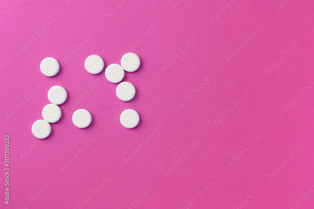 White round pills tablets on a bright pink background close up. Top view, copy space. Medical concept White round pills tablets on a bright pink background close up. Top view, copy space. Medical concept