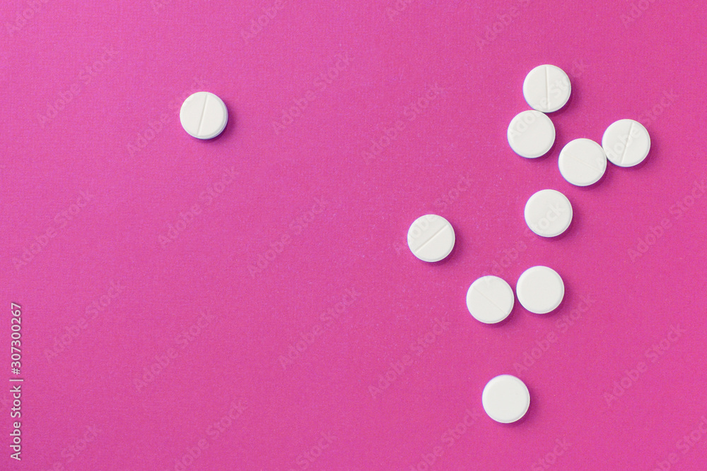 White round pills tablets on a bright pink background close up. Top view, copy space. Medical concept White round pills tablets on a bright pink background close up. Top view, copy space. Medical concept