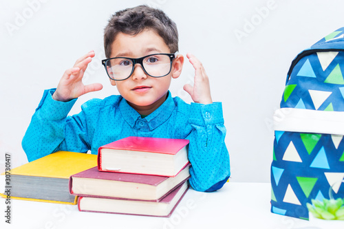 cute boy in glasses sitting at a Desk with books