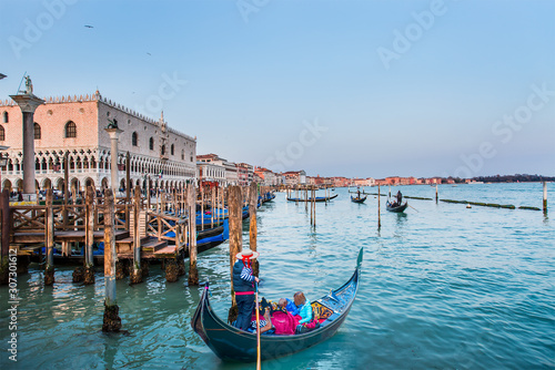 Venetian gondolier punting gondola through green canal waters of Venice Italy