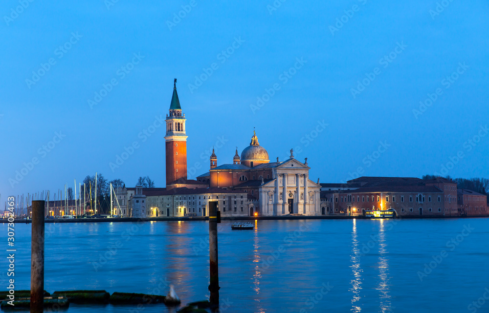 View of San Giorgio Island in Venice with wooden buoys in Giudecca Canal  at twilight blue hour - Venetian gondolier 